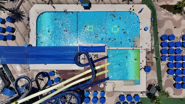Aerial Top Lockdown Shot Of People Enjoying In Swimming Pool At Yamit Water Park On Weekend During Sunny Day - Holon, Israel