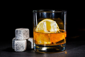 glass of whiskey with cooling stones. Dark gray bourbon stones.