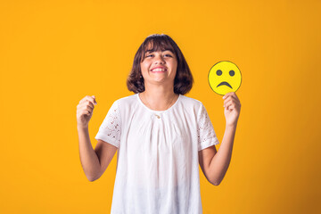 Girl smile and holds sad emoticon. Mental health, psychology and children's emotions concept