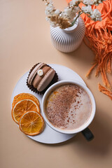 A cup of warm cocoa with a macaroon and cozy winter decor flat lay. Warm drink top view