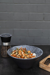 Bowl with tasty rice, meat and vegetables on dark background with space for text.