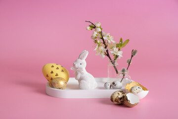 White rabbit, blossom twig and Easter eggs on a pink background. Easter composition