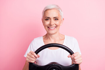 Photo portrait of lovely senior lady hold steering wheel driving lesson wear trendy white garment isolated on pink color background