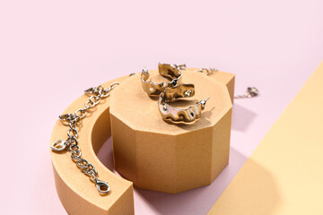 Decorative podiums with silver earrings and bracelet on color background