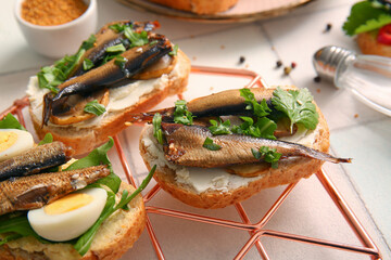 Grid of tasty sandwiches with canned smoked sprats on white tile background - obrazy, fototapety, plakaty
