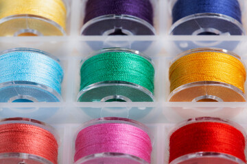 Plastic bobbins for a sewing machine with multi-colored threads. - obrazy, fototapety, plakaty