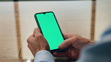 Man hand scrolling greenscreen smartphone indoor closeup. Manager holding phone