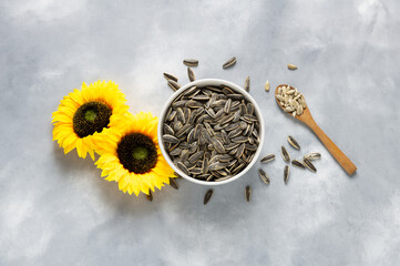 Pile of black roasted salty sunflower seeds with flower on rustic table, nut concept, Helianthus annuus
