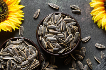 Pile of black roasted salty sunflower seeds with flower on rustic table, nut concept, Helianthus...