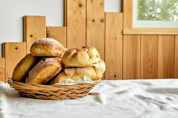 Homemade breadstuff. Just made bread rolls ready to eat in a wicker basket on the table.