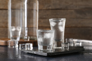 Shots and bottles of vodka on dark table