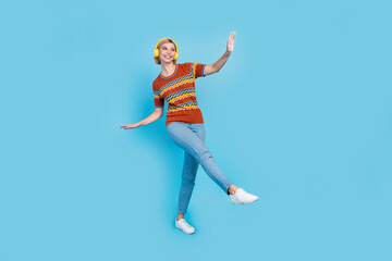 Fototapeta na wymiar Full length photo of good mood girl wear strited t-shirt in headphones dancing look at sale empty space isolated on blue color background