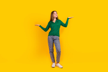 Full length portrait of nice young person look arms show empty space vs scales isolated on yellow color background