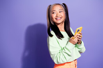 Photo of japanese blogging youth girl browsing phone looking new account tik tok in empty space isolated on violet color background
