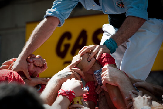 Hands of castellers making a Human Tower during Poble Sec neighborhood festivities  in Barcelona, Spain