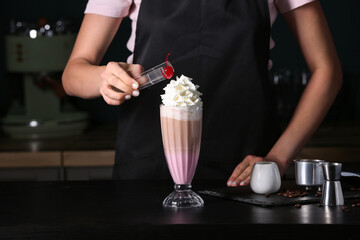 Barista making tasty latte with whipped cream in cafe