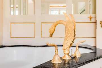 A gold swan faucet for a large bathtub in a luxury home.