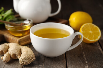 Cup of ginger tea and bowl with honey on wooden background