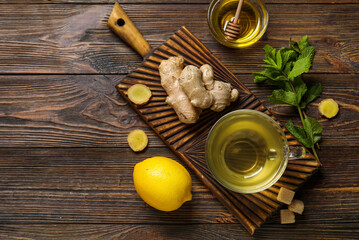 Glass cup of ginger tea with lemon and mint on wooden background