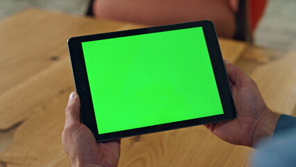 User holding chromakey computer indoors closeup. Man reading template device