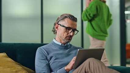 Eyeglasses man working tablet in office couch closeup. Director feeling tired