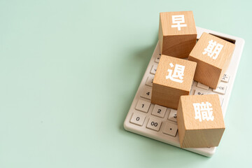 Obraz premium 早期退職の文字が入ったブロックと電卓