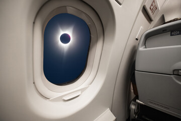 A solar eclipse looking through the window of an airplane