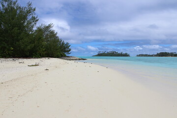 rarotonga clear water sky turquoise white beach bush and cloudy sky