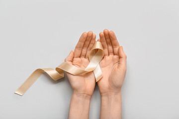 Woman with beige ribbon on light background. Uterine cancer awareness concept