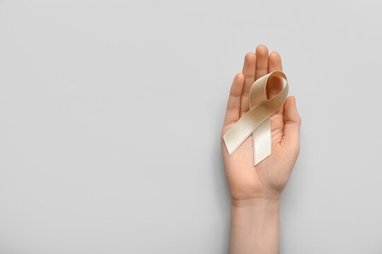 Woman with beige ribbon on light background. Uterine cancer awareness concept