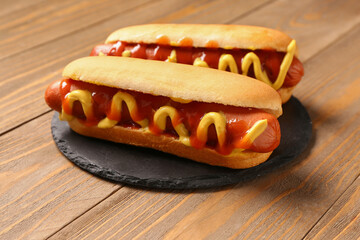 Board with tasty hot dogs on wooden background