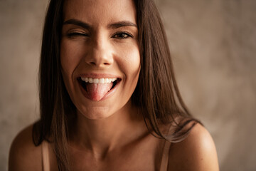 Portrait of playful young body positive no filter brunette hair girl stick tongue out posing joking...