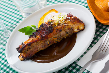 Appetizing broiled pork ribs in delicate chocolate sauce with vegetable garnish of baked potato,...