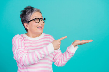 Photo of pretty dreamy woman dressed pink pullover eyewear pointing finger showing arm empty space isolated teal color background