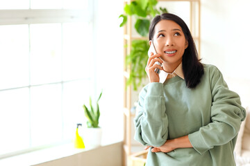 Young Asian woman talking by mobile phone at home