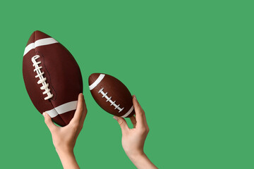 Female hands with balls for American football on green background - Powered by Adobe