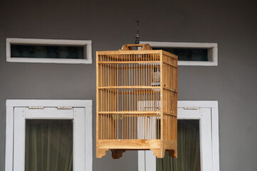 A traditional small bird cage hangs in front of the house