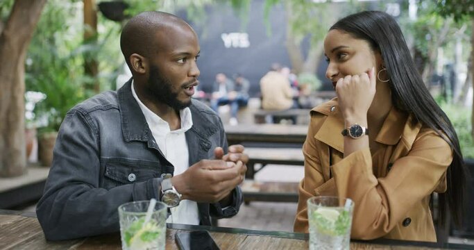 Couple, talking on date and drink at restaurant, communication and commitment, love and care. Interracial people, partner and trust with cold beverage, social and romantic at cafe for relationship