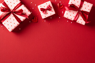 Valentine's Day. Gift boxes with confetti on red background. View from above