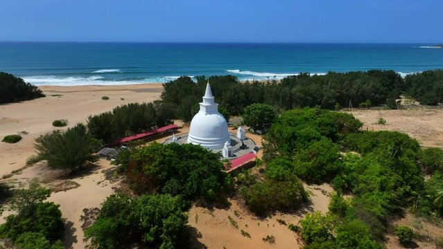Aerial Panning Shot Of Muhudu Mahavihara Ancient Royal Temple At Beach Against Clear Sky On Sunny Day - Pottuvil, Sri Lanka