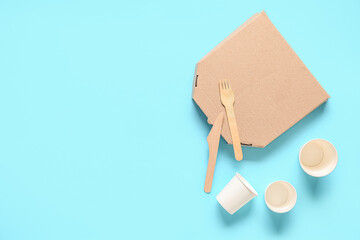 Takeaway paper cups, pizza box and cutlery on blue background