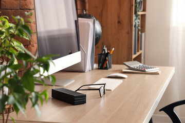 Blank computer monitor with stationery on table in office
