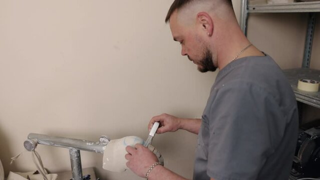 Mold creation, Mold development, Measurement precision. Using tape measure, man assesses size and diameter of hip disarticulation prosthetic leg mold he has created.