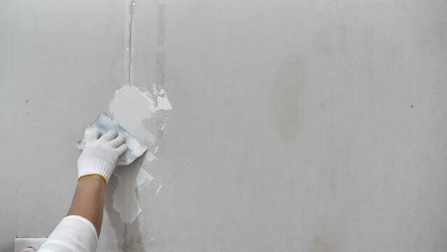 Plasterwork and wall painting preparation. close up hand of craftsman applying filling drywall patch.