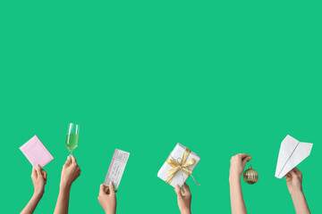 Female hands holding passport with ticket, paper plane and gift on green background. New year vacation concept