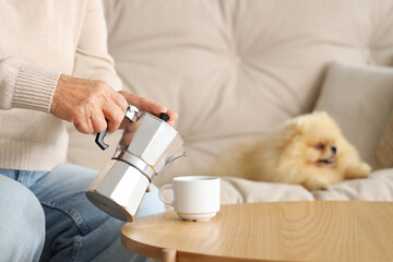 Senior woman pouring coffee into cup on table at home, closeup