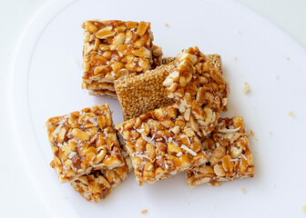 Peanut chikki and Til chikki on white background. peanut chikki and til chikki are an Indian sweet dishes made with jaggery, peanut and sesame. Indian festival Makar Sankranti special sweet.