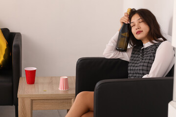 Drunk business woman with champagne sitting after New Year party in office