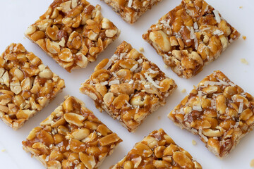 Peanut Chikki on white background. peanut Chikki is an Indian sweet dish made with jaggery and...