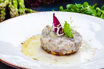 Sea bass tartare with toasted bread on a white plate